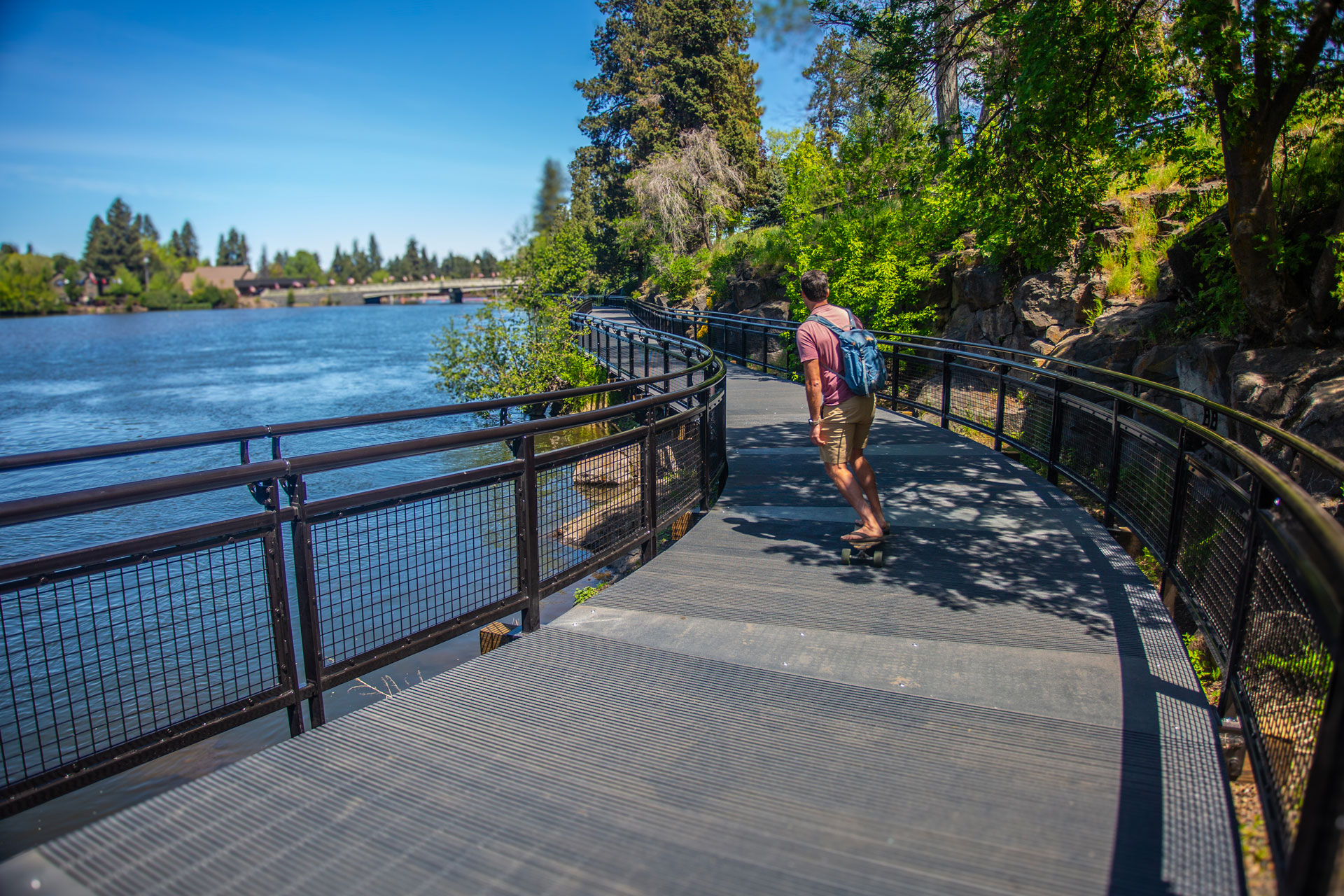 Person on skateboard rolls along the Drake Park boardwalk on a sunny day.