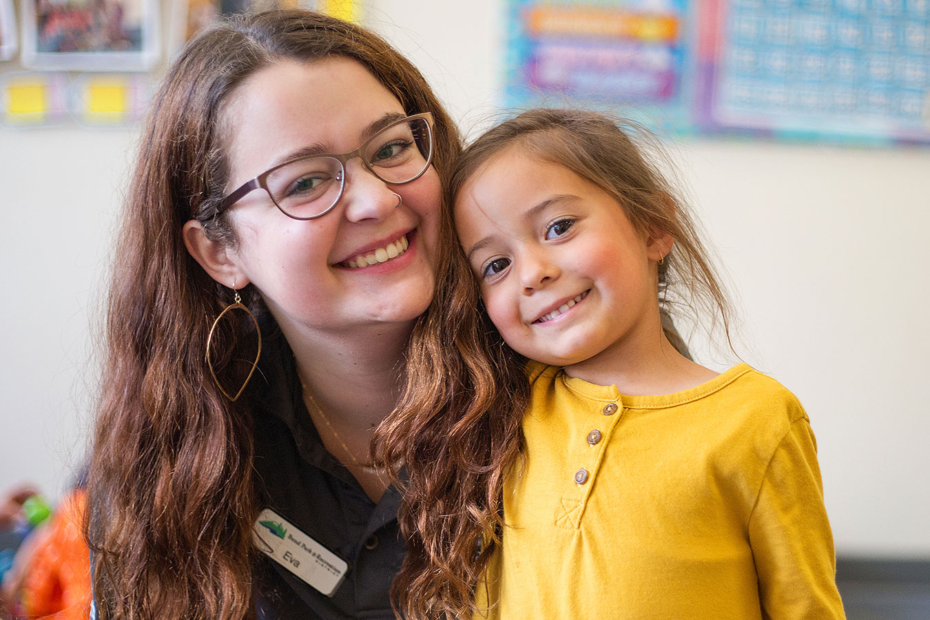 A BPRD childcare employee smiles with a young child.