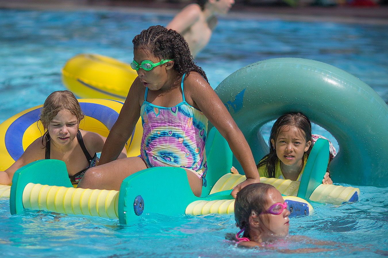 Several children playing on floatation toys in the activity pool at JSFC