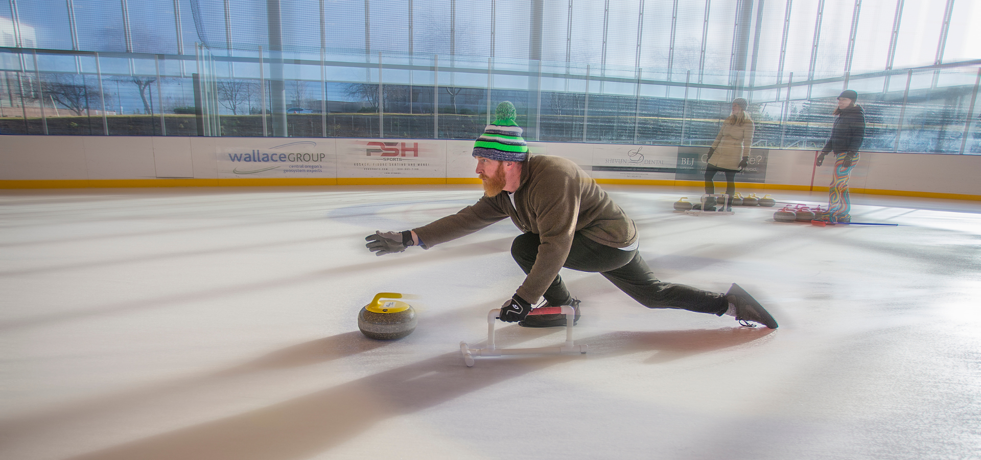 At the Pavilion, a curling player throws their stone across the ice.
