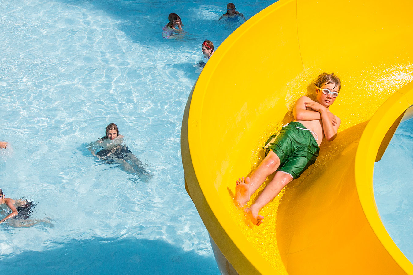 A kid is riding down the yellow water slide at Juniper.