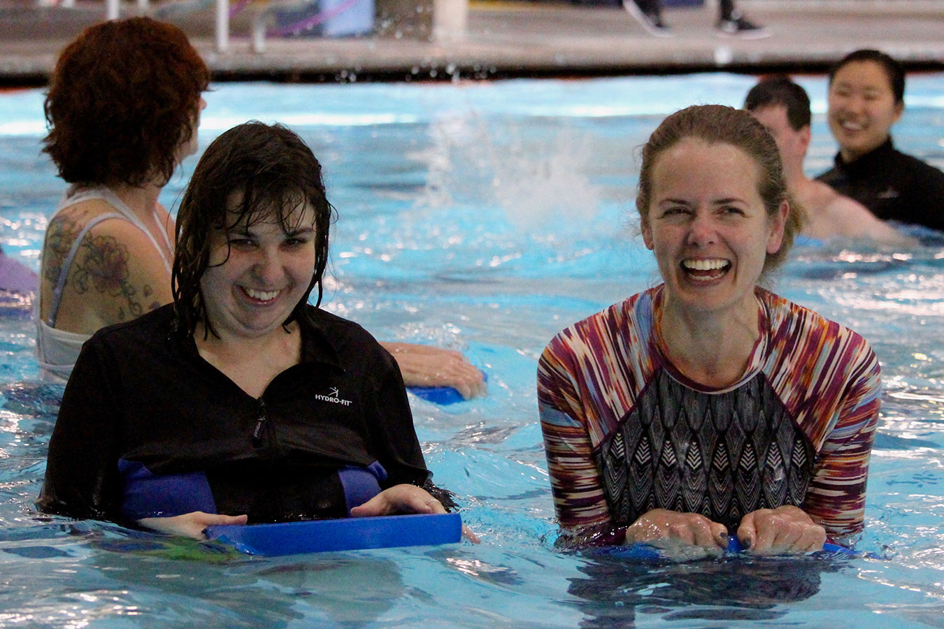 A theraeutic recreation instruction smiles with a patron in the pool.