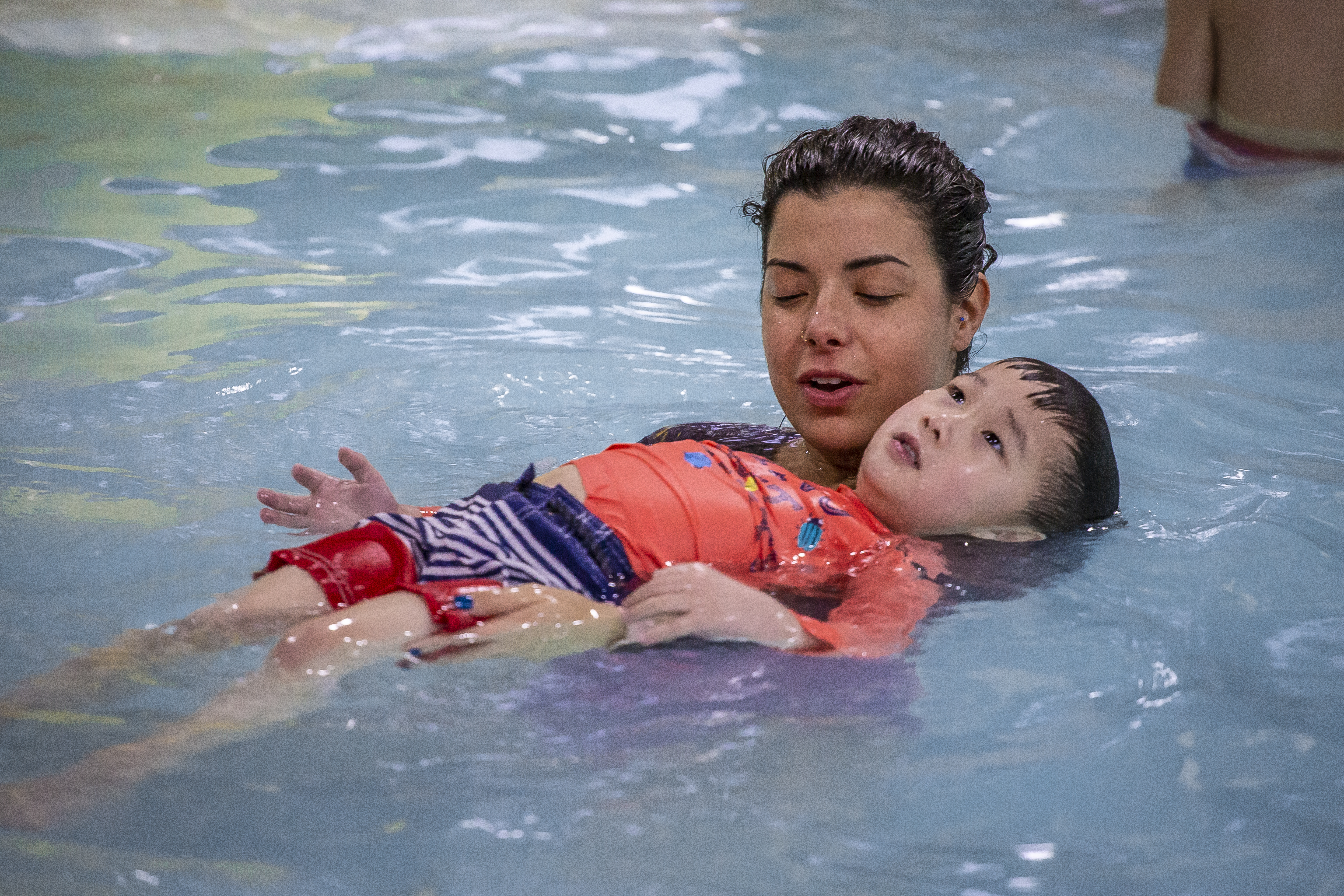 Instructor helps a child learn to float at Juniper