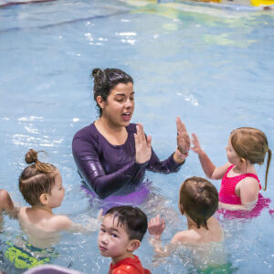 An instructor is addressing a group of five children in the pool at Juniper