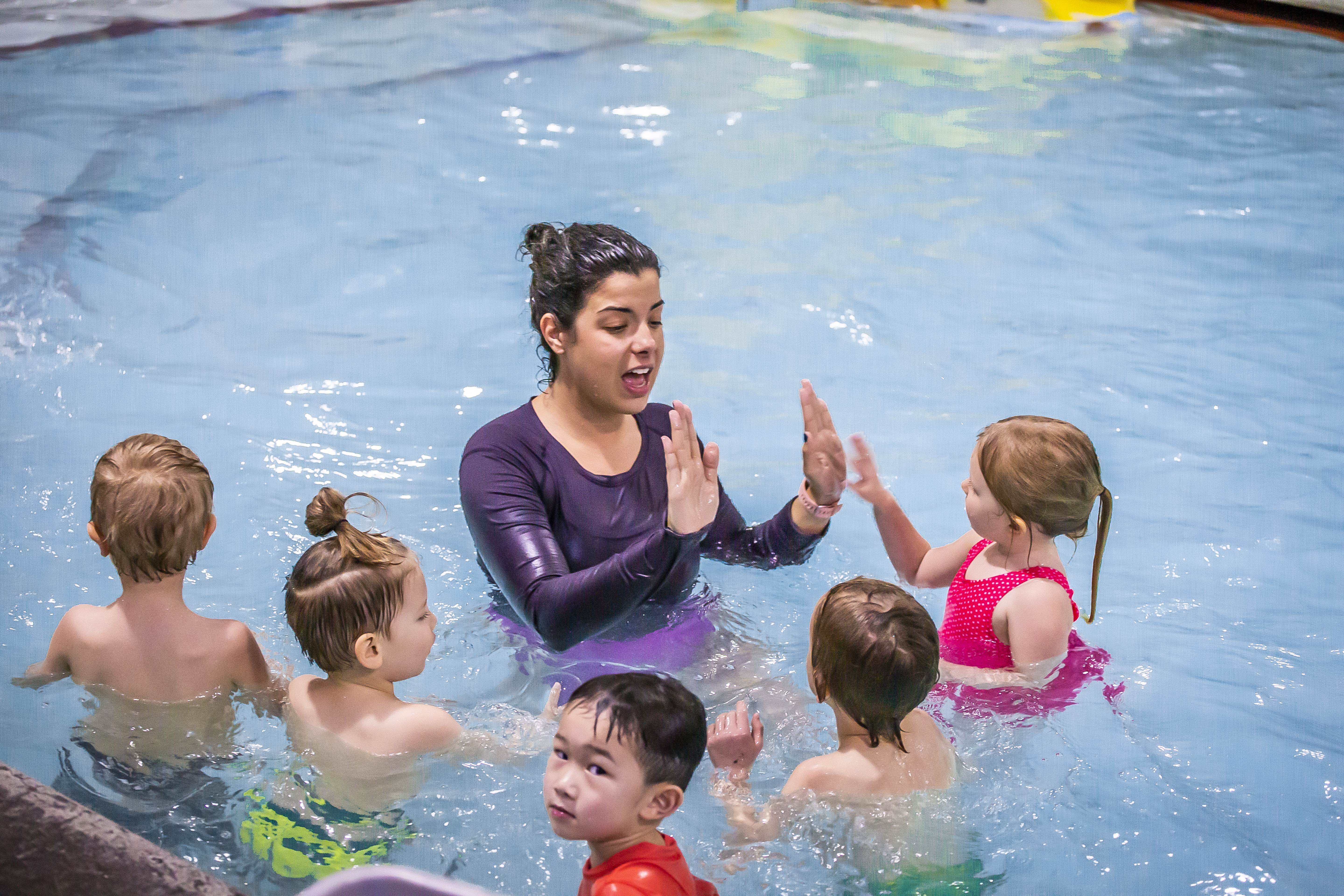 An instructor is addressing a group of five children in the pool at Juniper