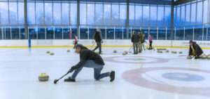 Man on the ice releases a curling stone at the Pavilion.