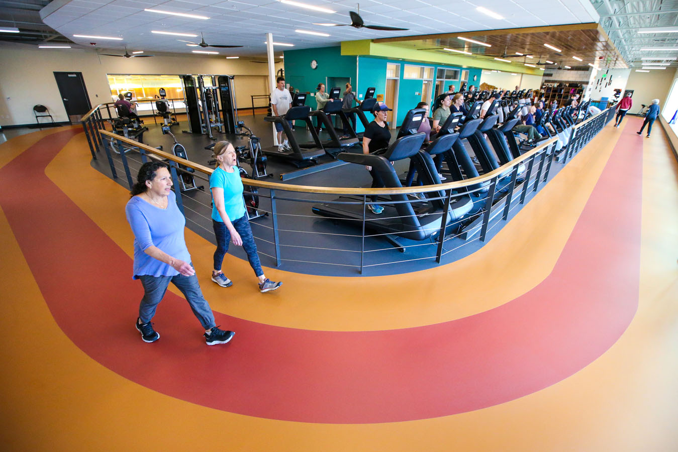 Two patrons walk around the indoor track at Larkspur while others use the running machines.