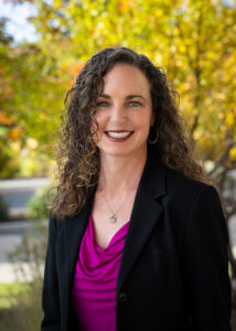 Photograph of Jodie Barram looking directly forward with trees in the background.