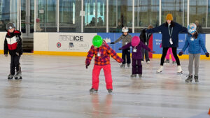 A group of young children are learning to ice skate at the Pavilion.